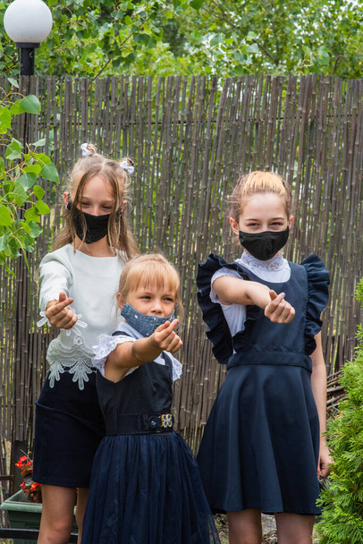 Três alunas usando máscaras e voltando para a escola durante a pandemia do covid-19. Três alunas com máscaras protectoras. Vírus, bactérias, escola, protecção. Meninas adolescentes em uniforme escolar - Foto, Imagem