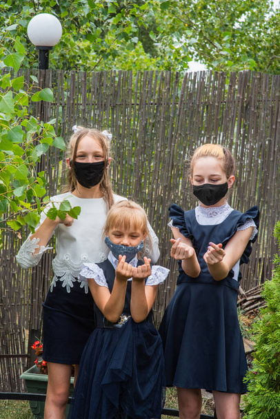 Három iskolás lány maszkot visel és visszamegy az iskolába a Covid-19-es járvány idején. Három iskoláslány védőmaszkot visel. Vírus, baktérium, iskola, védelem. Tini lányok iskolai egyenruhában. - Fotó, kép