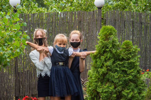 Três alunas usando máscaras e voltando para a escola durante a pandemia do covid-19. Três alunas com máscaras protectoras. Vírus, bactérias, escola, protecção. Meninas adolescentes em uniforme escolar - Foto, Imagem