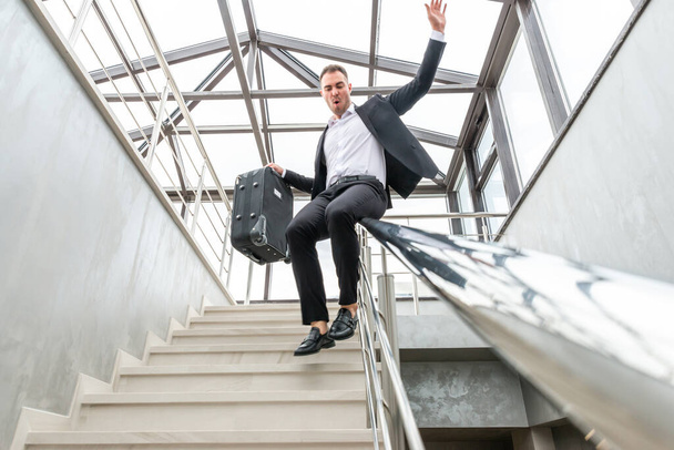 階段で滑り正式なスーツを着て幸せなビジネスマン近代的なビジネスビルでの鉄道。急いで自由の概念 - 写真・画像