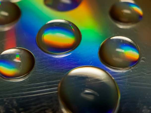 L'eau laisse tomber les disques CD réfléchissant la lumière. Cette lumière est bleue, jaune et verte. - Photo, image