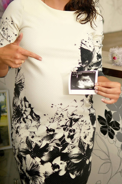 pregnant woman shows a photo of the unborn child - Φωτογραφία, εικόνα