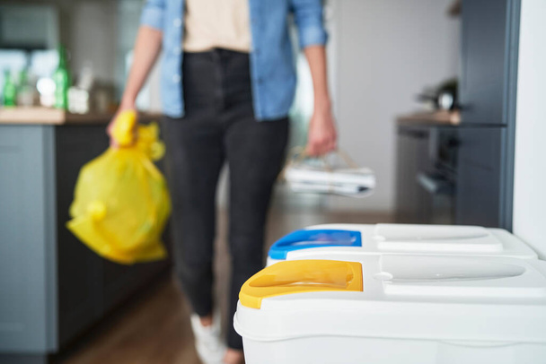 Femme va à la poubelle avec sac en plastique jaune - Photo, image