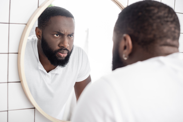 hombre afro-americano serio mirando el reflejo en el espejo - Foto, imagen