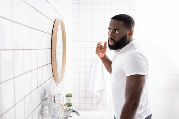 hombre afro-americano mirando la cara en el espejo - Foto, Imagen