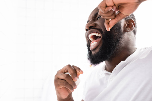 バスルームで歯科用フロスを使うアフロアメリカ人男性は - 写真・画像