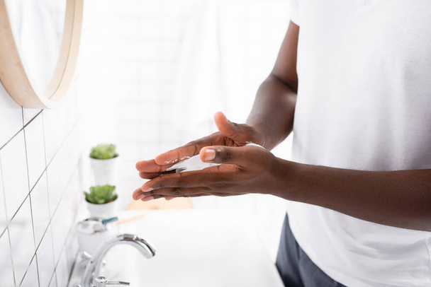 vista recortada del hombre afroamericano aplicando espuma de afeitar con las manos - Foto, imagen