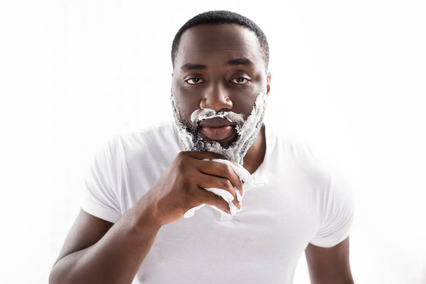 афроамериканський чоловік з піною для гоління на обличчі дивиться на камеру
 - Фото, зображення