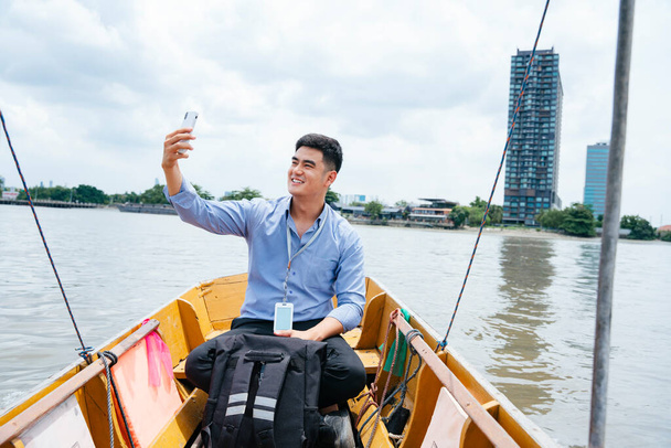 Asian business man taking photo with smartphone and travel by a boat in Bangkok. - Fotoğraf, Görsel