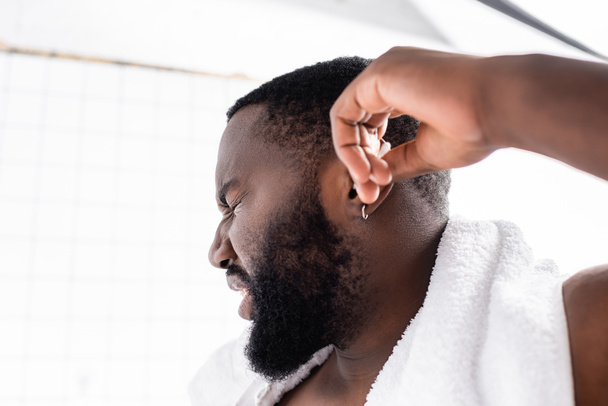 retrato de hombre afroamericano limpiando oídos con dolor - Foto, imagen