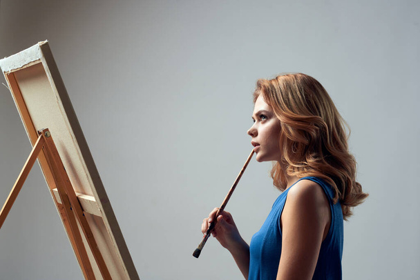 Mujer artista con pintura de pincel sobre caballete arte hobby fondo claro - Foto, Imagen