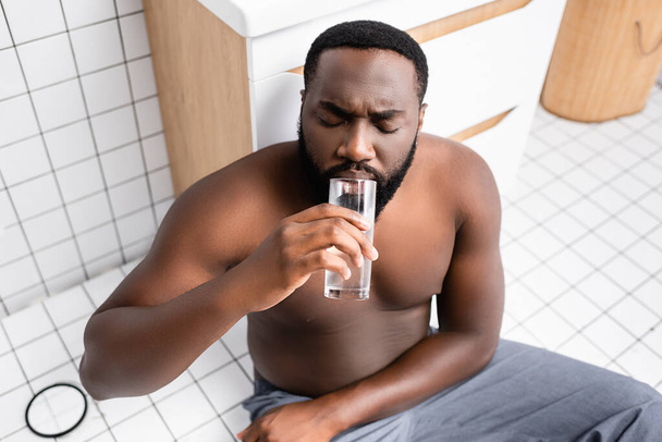 uomo afro-americano che soffre di postumi di sbornia e acqua potabile - Foto, immagini