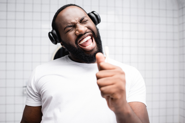 Afroamerikaner mit Kopfhörern singt in Zahnbürste - Foto, Bild