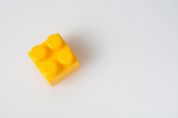 Жовтий куб-блок конструктора на білому тлі з копіювальним простором. Концепція будівництва
. - Фото, зображення