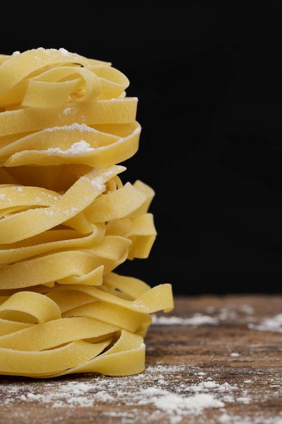 Nahaufnahme Raw Tagliatelle Pasta auf schwarzem Hintergrund - Foto, Bild