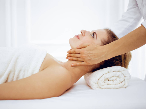 Jeune femme blonde profitant d'un massage facial dans un salon de spa. Concept de beauté - Photo, image