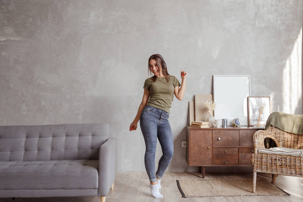 Young woman with wireless headphones dancing and listening to music at home - Photo, Image