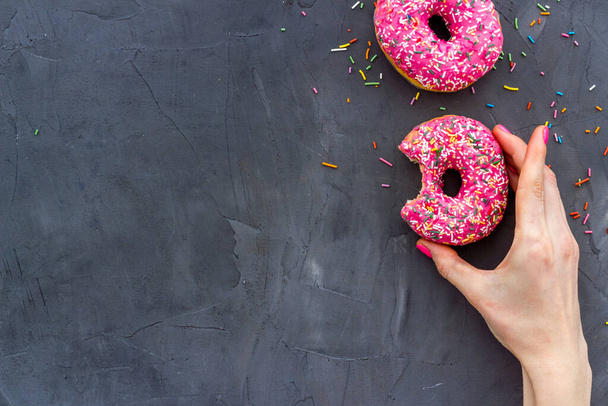 Hand holding glazed donut swith sprinkles, above view - Zdjęcie, obraz