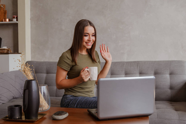 Szczęśliwa młoda kobieta machając ręką podejmowania odległość wideo rozmowy czat online patrząc na ekranie laptopa siedzieć na kanapie, uśmiechnięta dziewczyna śmiejąc się rozmawiać z kamerą internetową komunikacji przez komputer internetowy PC app w domu - Zdjęcie, obraz
