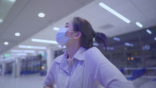 若い女性は、飛行時間画面を見て顔マスクを着用,空の空港ターミナル内, covid-19パンデミックの間の旅行のリスク,新しい正常な社会的距離,送信疾患予防,フロントビュー - 映像、動画