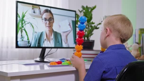 koulupoika alas oireyhtymä opiskelee verkossa kotoa, oppilas värillisiä leluja kellot web-luokan oppitunti ja kuuntelee opettajaa videopuhelu istuu comp - Materiaali, video