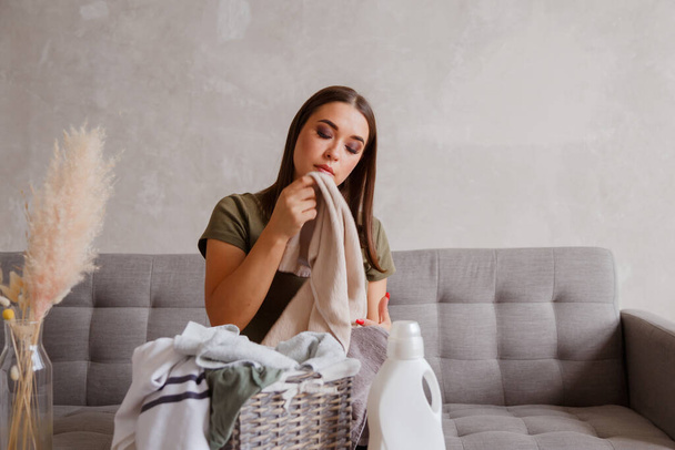 Chica disfruta de toallas limpias y olorosas después de lavar con nuevo gel detergente. - Foto, Imagen