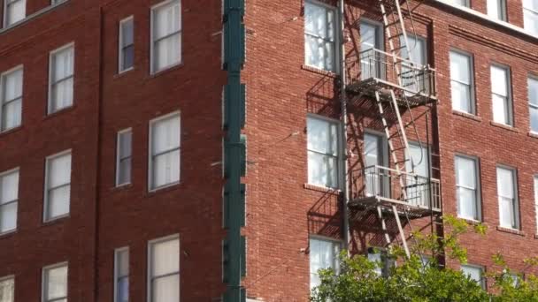 Drabinka przeciwpożarowa przed budynkiem mieszkalnym z cegły w San Diego, USA. Typowe wyjście awaryjne w stylu Nowego Jorku dla bezpiecznej ewakuacji. Klasyczny retro dom zewnętrzny jako symbol nieruchomości - Materiał filmowy, wideo