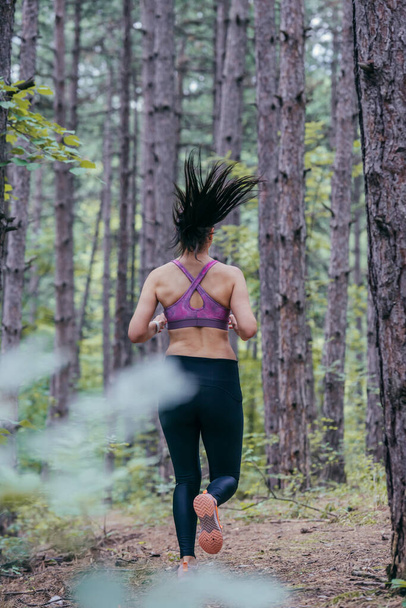 Obrázek z pozadí mladé sportovní ženy běžící lesem - Fotografie, Obrázek