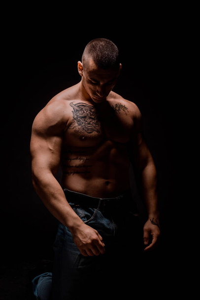 Vahva ja komea nuori mies osoittaa hänen lihaksikas vartalo ja hauis - Valokuva, kuva