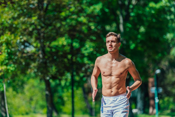 Close-up portrait of a handsome male athlete running shirtless on a sunny day - Photo, Image