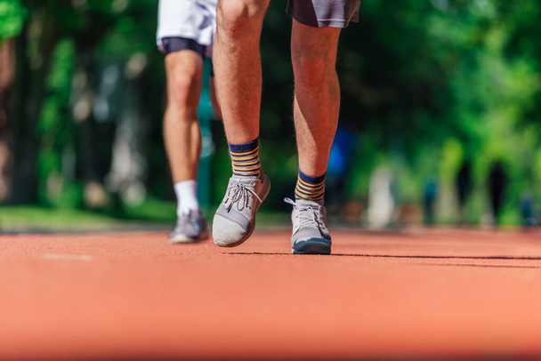 Cerrar los pies con zapatos de correr y fuertes piernas atléticas de hombre deportivo corriendo en la pista de atletismo - Foto, Imagen