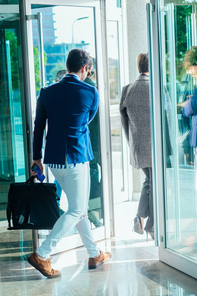 Empresaria y su colega varón saliendo del edificio de oficinas con puertas de cristal. - Foto, Imagen