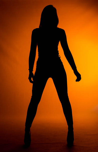 Stylová módní dívka pózující v módní oblečení proti oranžovému pozadí - Fotografie, Obrázek