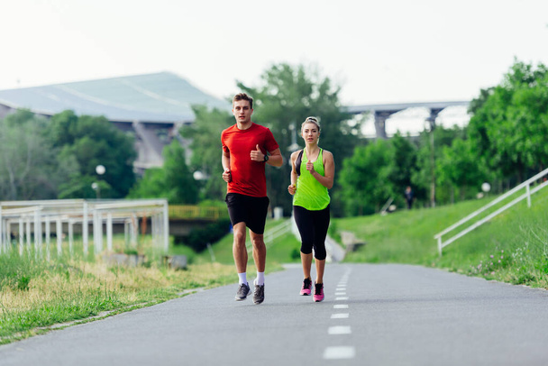 Mladý běžecký pár jogging na asfaltové cestě v parku - Fotografie, Obrázek