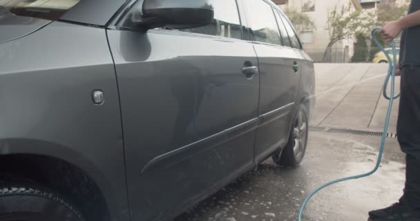Αγόρι πλένει το αυτοκίνητο του πατέρα του μπροστά από το γκαράζ μια ηλιόλουστη μέρα - Πλάνα, βίντεο