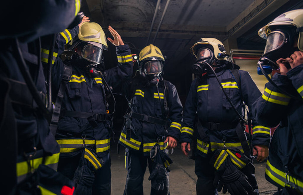 Команда пожарных в пожарной части в противогазах и униформе - Фото, изображение