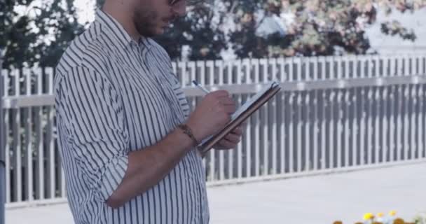 Uomo d'affari che lavora a distanza, scrivendo i suoi pensieri su un pezzo di carta - Filmati, video