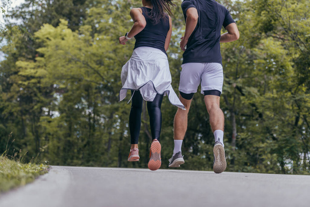 Jeune couple en forme atheltes courir sur la route de course dans une forêt. - Photo, image