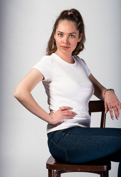 Körperbild einer stilvollen Frau, die in trendigen Jeans und weißem Top posiert - Foto, Bild