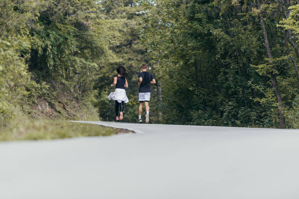 Fiatal pár atheltes fut futóúton egy erdőben. - Fotó, kép