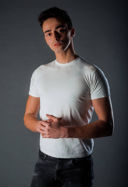 Πορτρέτο ενός νεαρού ελκυστικού άνδρα ντυμένου με λευκό μπλουζάκι - Φωτογραφία, εικόνα