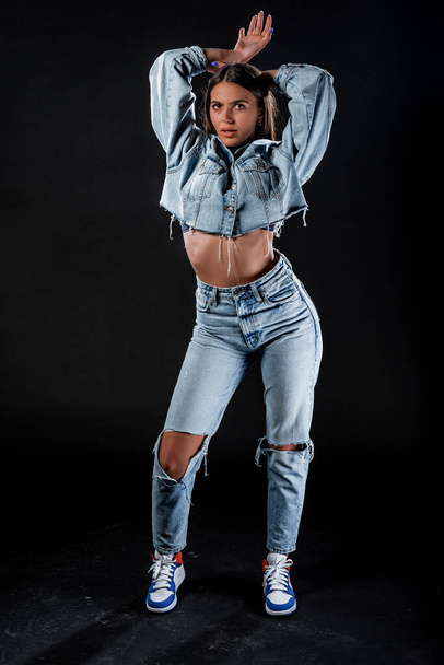 Modelo feminino jovem atraente posando em calças jeans azuis elegantes e jaqueta jean - Foto, Imagem