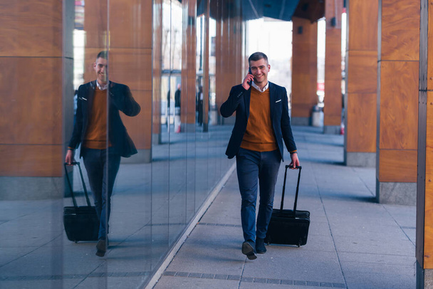 Gros plan photo un homme d'affaires formel traînant sa valise, son sac à main, son sac à main dans un aéroport (gare) - Photo, image