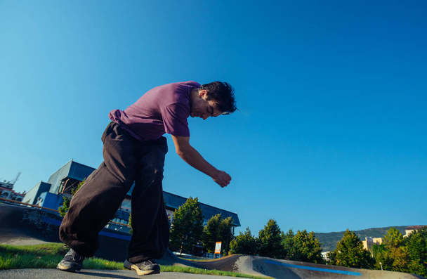Mladý muž cvičí parkour cvičení v místním skateparku za slunečného dne - Fotografie, Obrázek