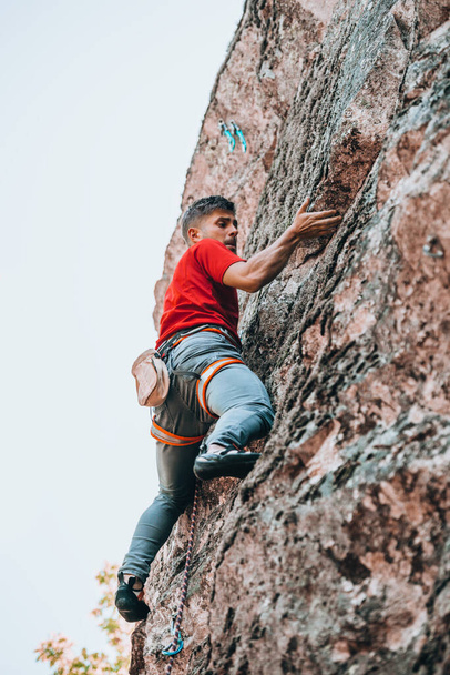 Mies harrastaa kiipeilyä. Kiipeilijä kiipeää kalliolle. Ulkoilu - Valokuva, kuva