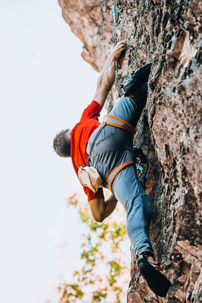 Jongeman klimmen op een uitdagend parcours op een klif oefenen voor atletiek - Foto, afbeelding