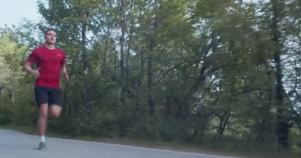 Człowiek biegnący w zwolnionym tempie po górskiej drodze, kamera dolly, pełny strzał - Materiał filmowy, wideo