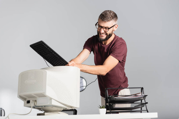 Őrült üzletember billentyűzet verte számítógép monitor elmosódott előtérben az irodában - Fotó, kép