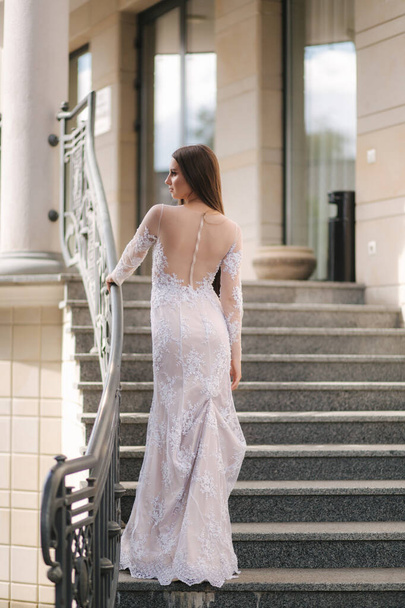 Привлекательная молодая женщина в красивом платье стоять на лестнице - Фото, изображение