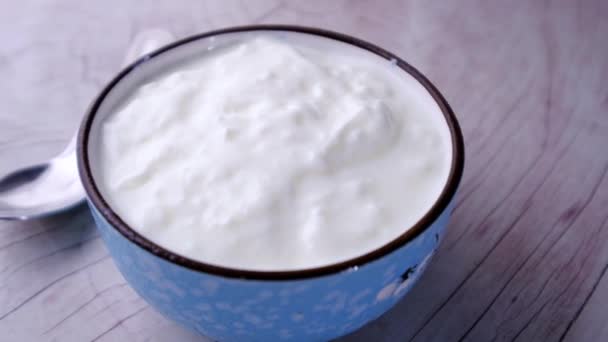 gros plan de yaourt frais dans un bol sur fond de bois  - Séquence, vidéo